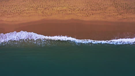 White-capped-ocean-waves-slowly-breaking-on-sandy-Thailand-coast-beach