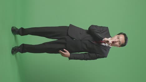 full body of asian business man showing silence gesture on green screen background in the studio