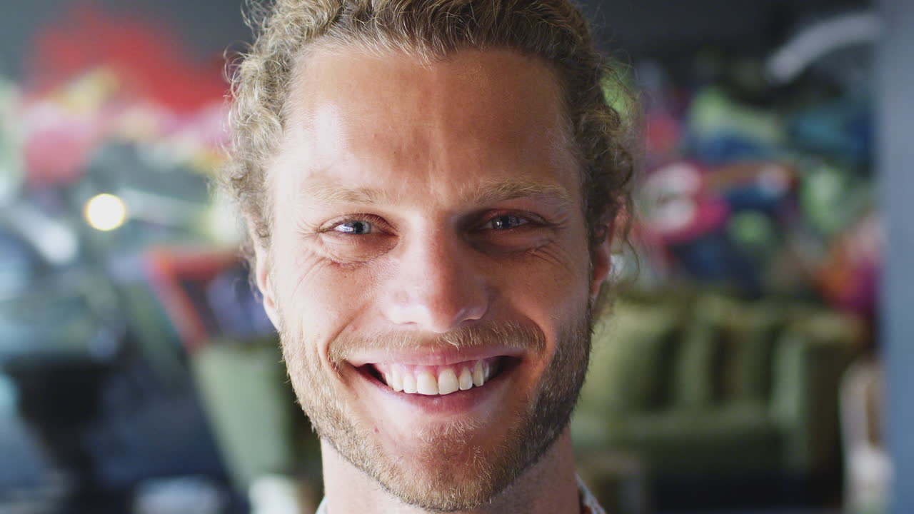 Jonge blanke man lachend naar de camera voor een muurschildering op de werkplek, close-up, portretfoto