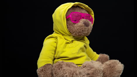 teddy bear in a yellow hoodie with pink sunglasses