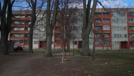 desolate worn out swing in playground in front of soviet apartment building