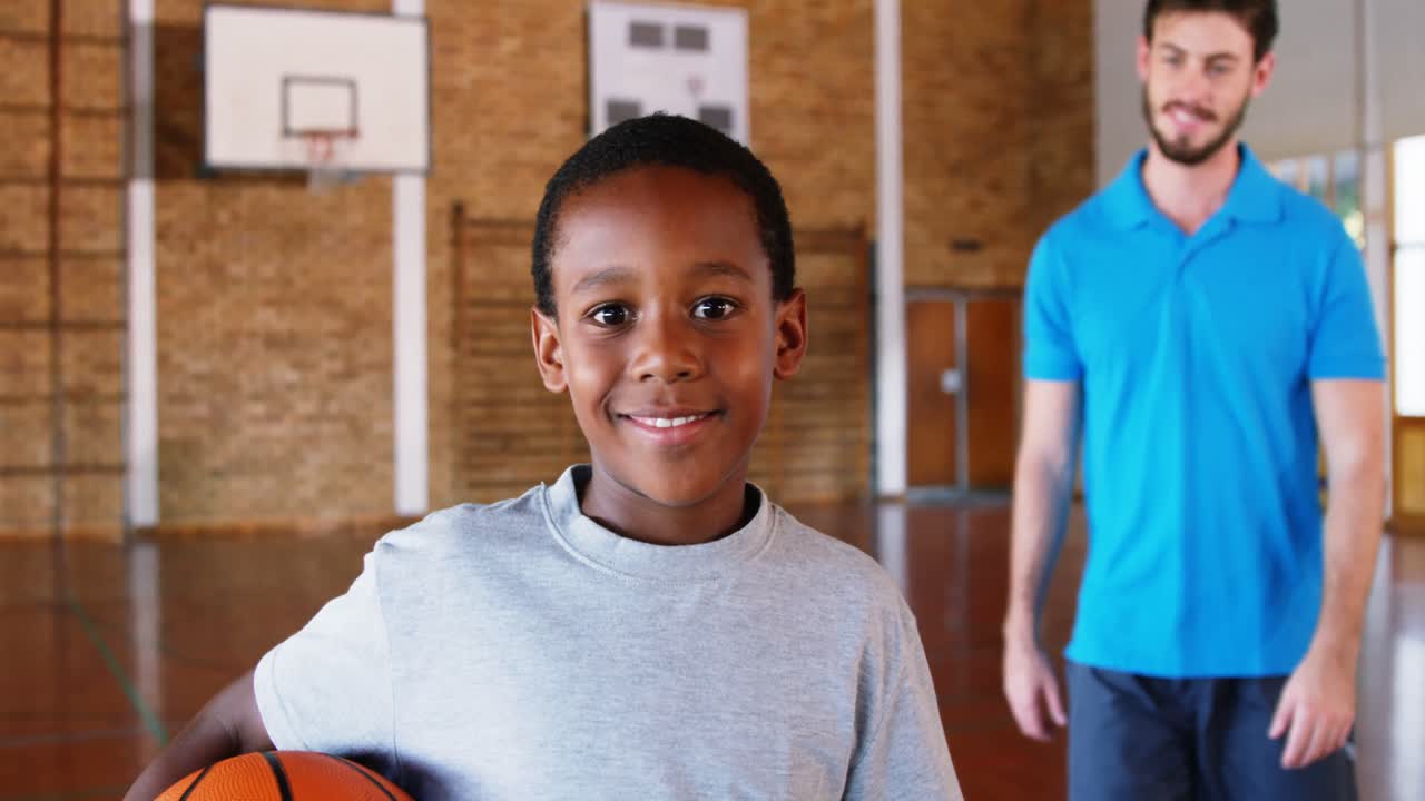 maestro de deportes de pie con su estudiante en la cancha de baloncesto