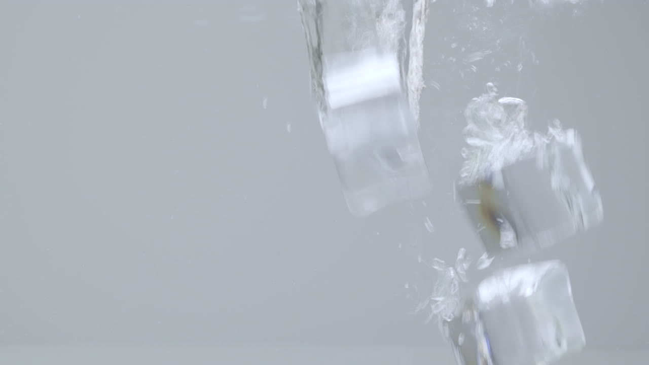 Ice cubes falling into water in slow motion