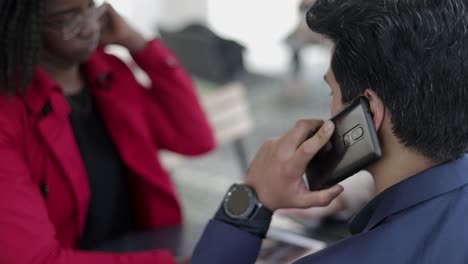 woman showing photos on tablet to couple, man talking on phone