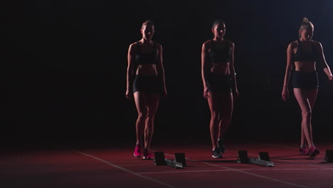 Female-runners-at-athletics-track-crouching-at-the-starting-blocks-before-a-race.-In-slow-motion.