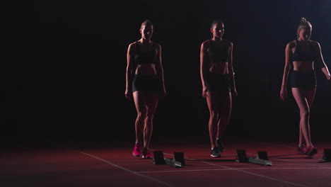 corredoras en la pista de atletismo agachadas en los bloques de salida antes de una carrera. en cámara lenta.