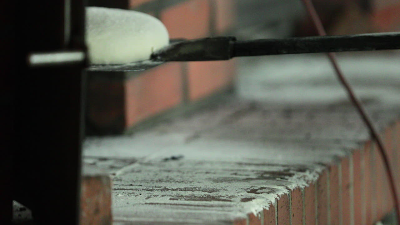빵 굽는 사람은 반죽한 반죽을 빵 껍질 위에 놓고 빵집의 오븐에 밀어 넣습니다. - 닫히고 패닝 샷