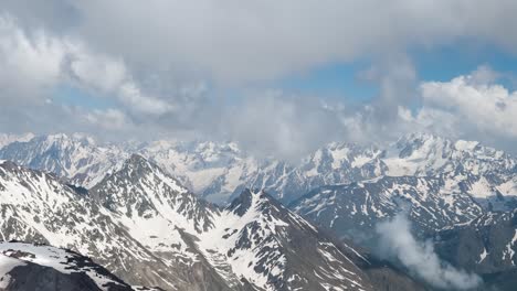 Air-flight-through-mountain-clouds-over-beautiful-snow-capped-peaks-of-mountains-and-glaciers.