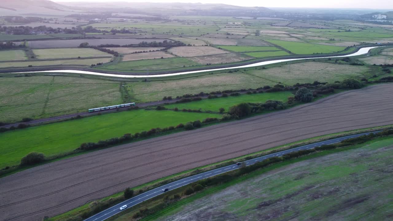 tren y coches conducen a través del campo junto al río