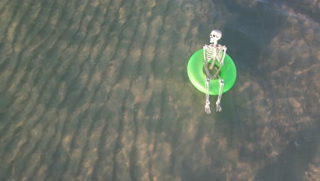 A-skeleton-on-gree-floats-in-the-clear-waters-of-the-Gulf-of-Mexico-floating-a-ba-bright-sunny-fall-day-for-Halloween