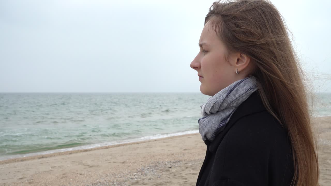 The girl looks at the sea. Shooting on the beach