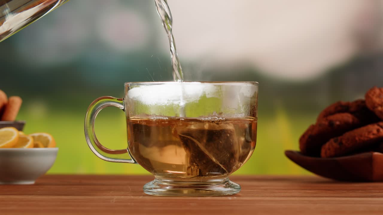 Pouring hot water into a glass mug to brew tea