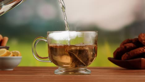 pouring hot water into a glass mug to brew tea