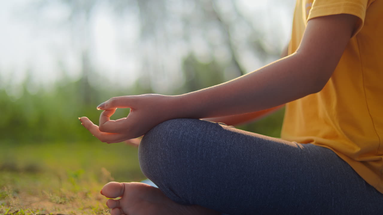 Close up shot of a serene women sitting in padmasana meditation pose during golden hour in the forest