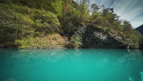 dense vegetation covering the shores of the loen lake is reflected in still turquoise waters