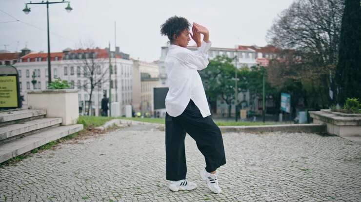 African girl performing dance on town. Woman choreographer moving body vertical