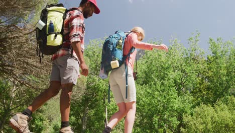 happy diverse couple hiking with backpacks in park, slow motion