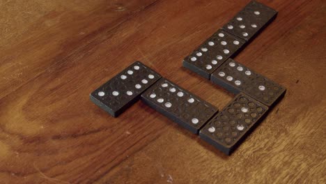 right hand sets black domino game tile with white dots onto table top