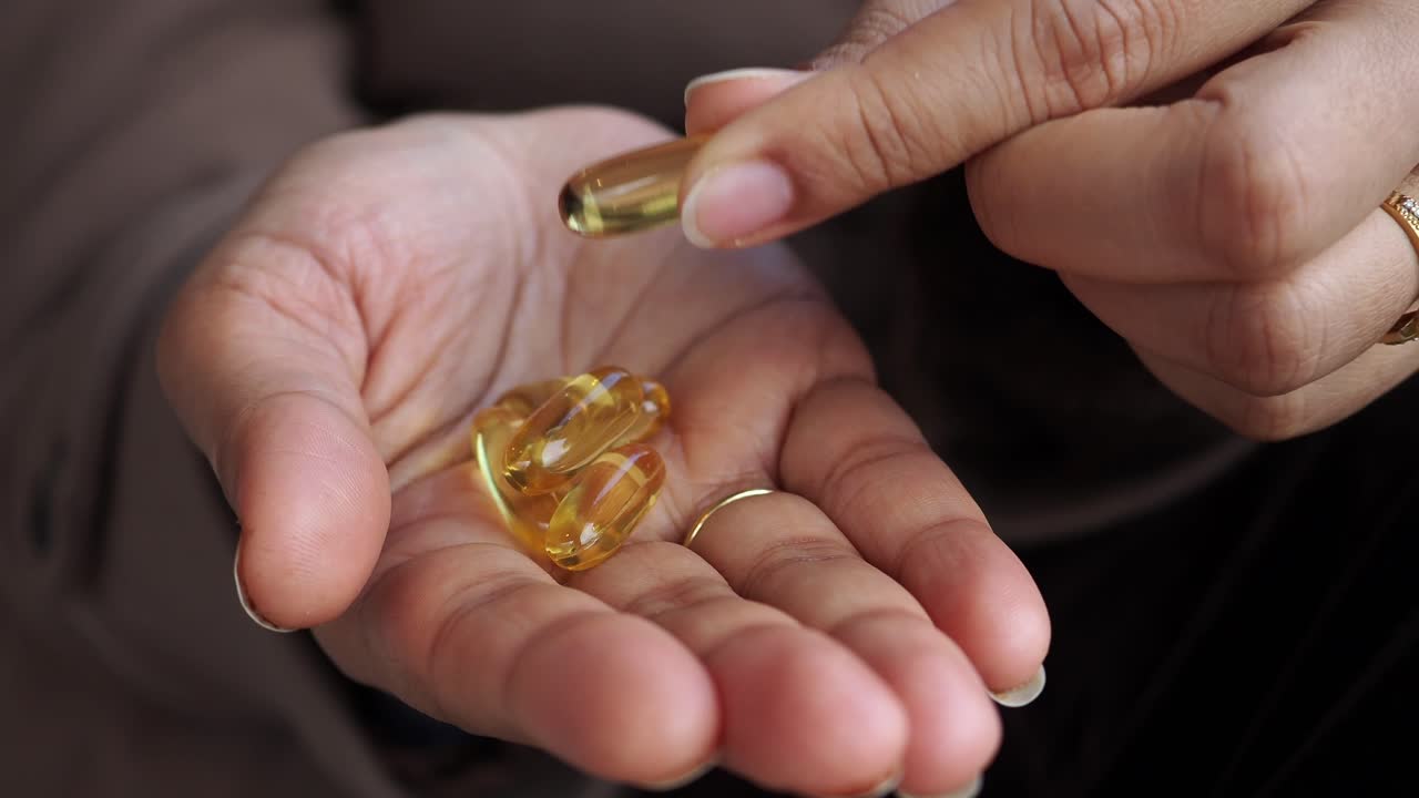 Primo piano di una mano che tiene capsule molli gialle