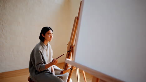woman painting on an easel in a studio