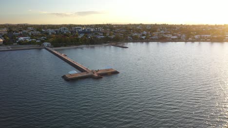 Wunderschöner-Sonnenuntergang-Aus-Der-Luft-über-Einer-Küstenstadt-Mit-Langem-Steg-Für-Fischer,-Wanderer,-Jogger,-Familien-Und-Älteste-In-Wynnum,-Queensland