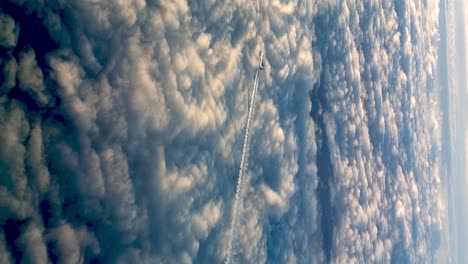 Incredible-flying-airplane-over-clouds,-high-angle-aerial-view