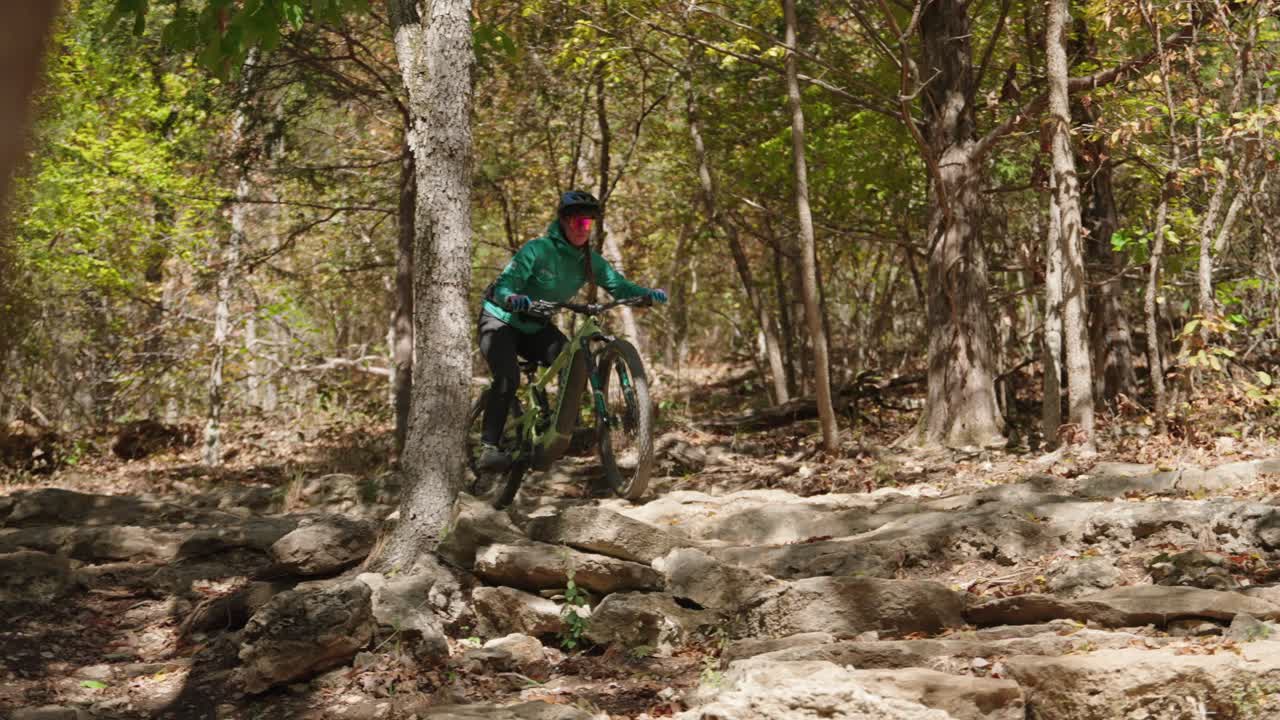 una mujer montando una sección técnica de roca de ciclismo de montaña en un sendero en bentonville arkansas, un destino principal en los estados unidos para el ciclismo de montaña