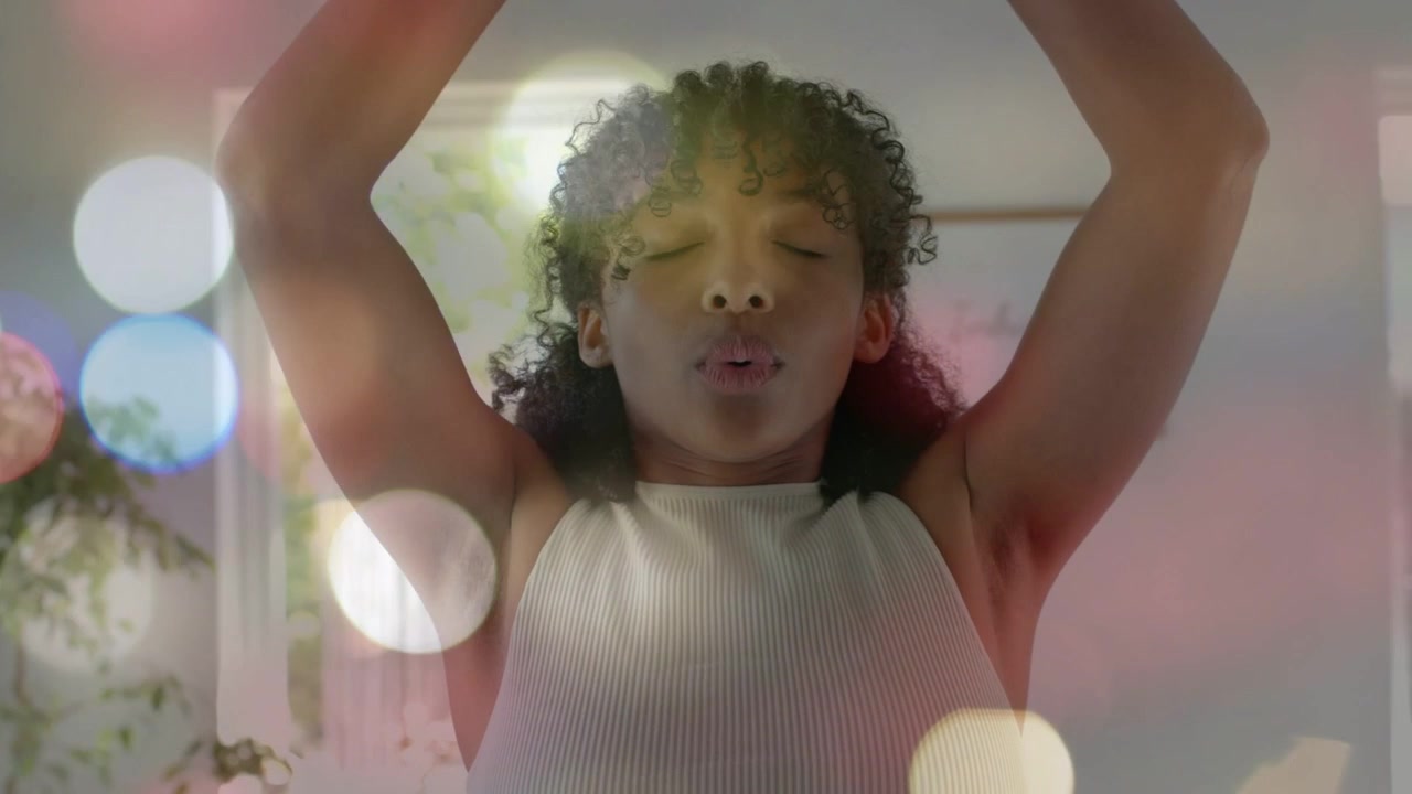 Teen female doing health breathing with hands pressing chest lifting arms as bokeh floating around