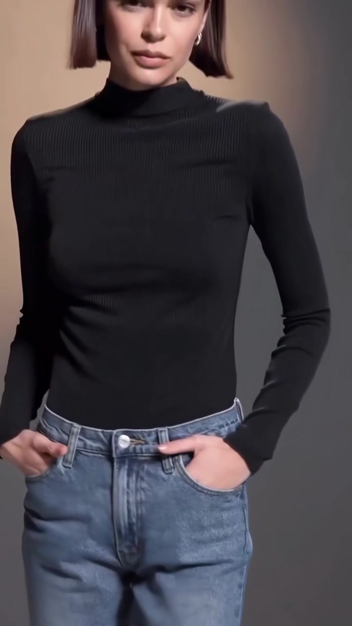 Giovane donna elegante in posa con dolcevita nero e jeans blu