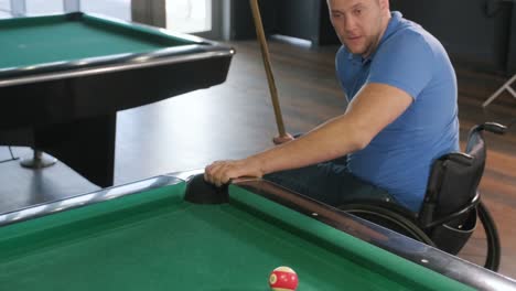 adult men with disabilities in a wheelchair play billiards in the club