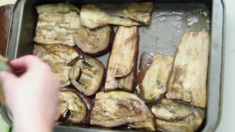 woman laying pre-cooked eggplant slices in the tray