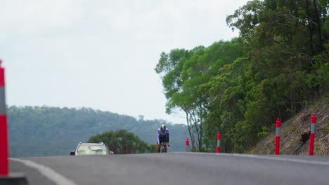 Professioneller-Radfahrer,-Der-Fahrrad-Auf-Gemeinsamer-Straße-Fährt,-Mit-Dem-Auto-Dahinter,-Bergauf,-4k