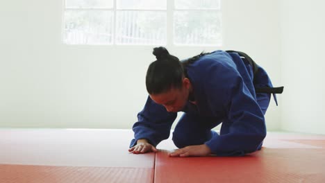 kneeling judoka saluting on the judo mat