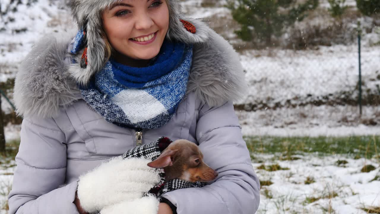 mujer jugando con su pequeño perro fuera del invierno