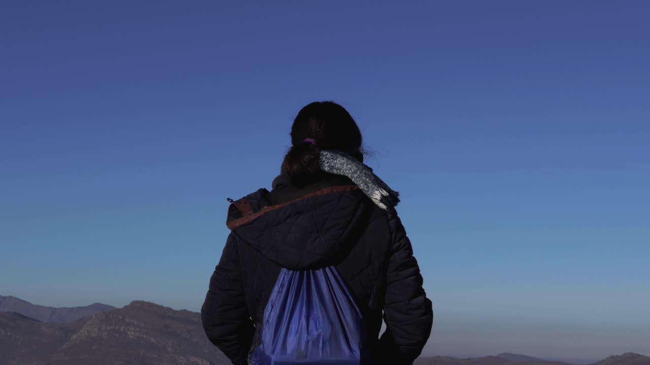 높이 서서 수평선에 있는 산을 바라보는 소녀의 뒷모습