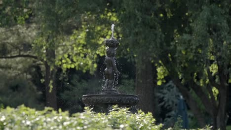 child statue fountain with water spraying in a green park