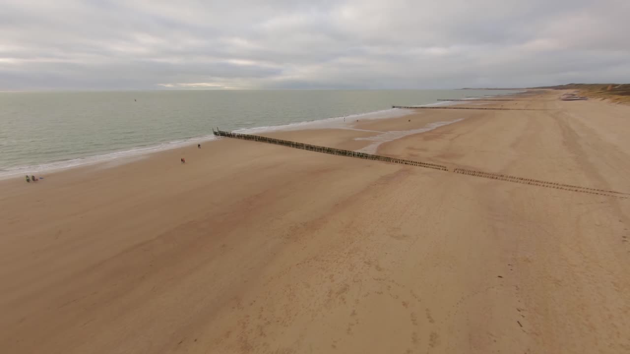 Drone diving over a high dune towards the beach and the sea