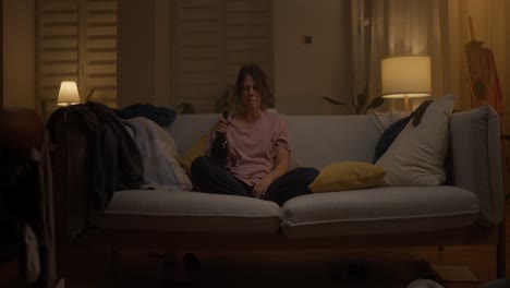 mujer bebiendo sola en el sofá
