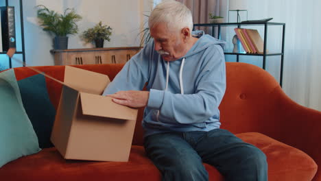 happy senior man shopper unpacking cardboard box delivery parcel online shopping purchase at home