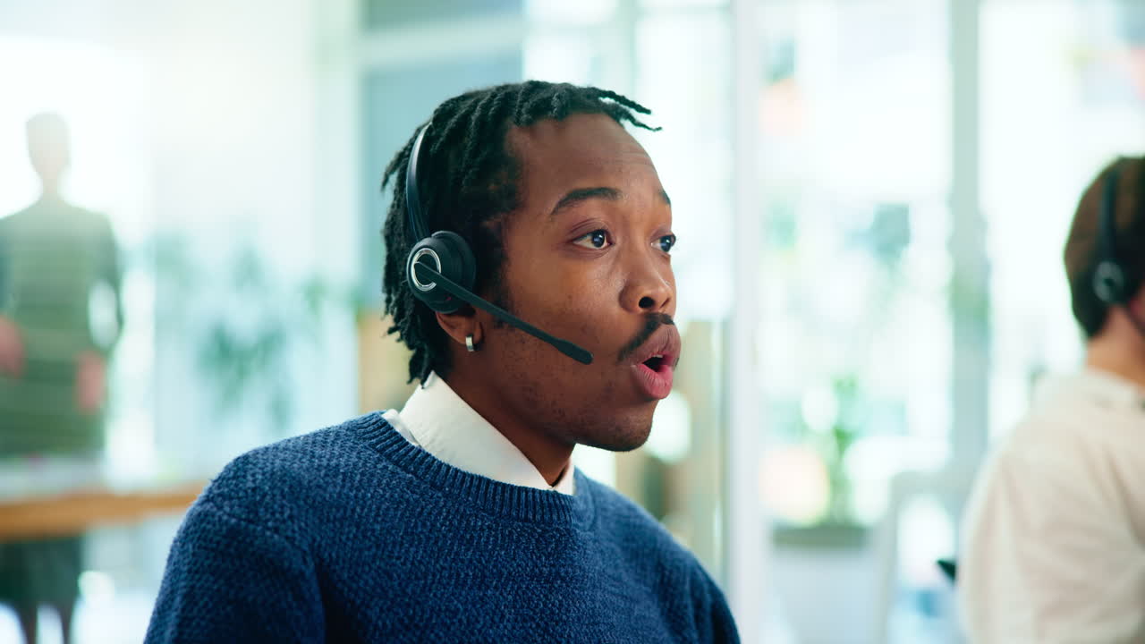 A man in a call center wearing a headset and talking on the phone.