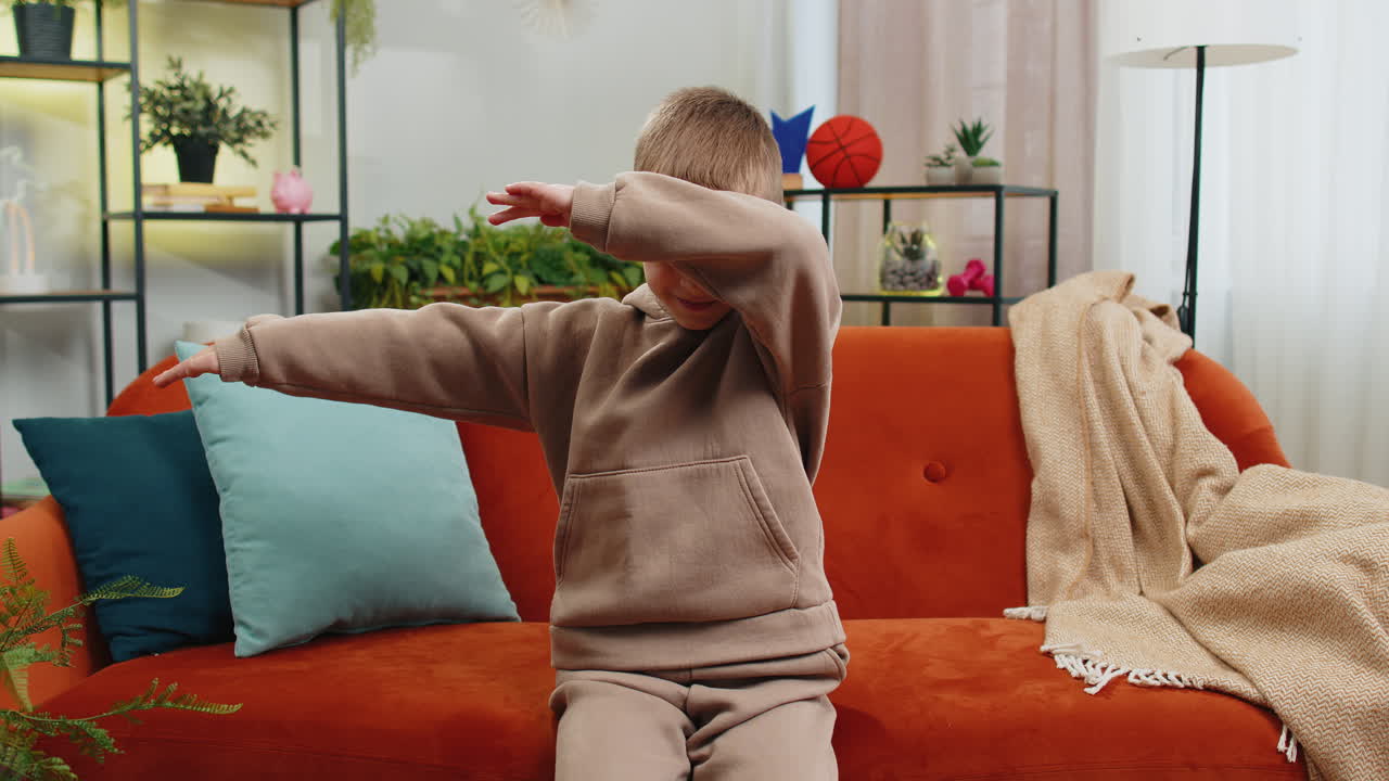 Happy toddler child boy dancing and moving to rhythm making trendy dub dance gesture at modern home