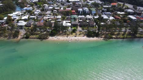 tourists on the white sand beach - waterfront houses at tallebudgera creek - vehicles travelling at the tallebudgera bridge in queensland, australia