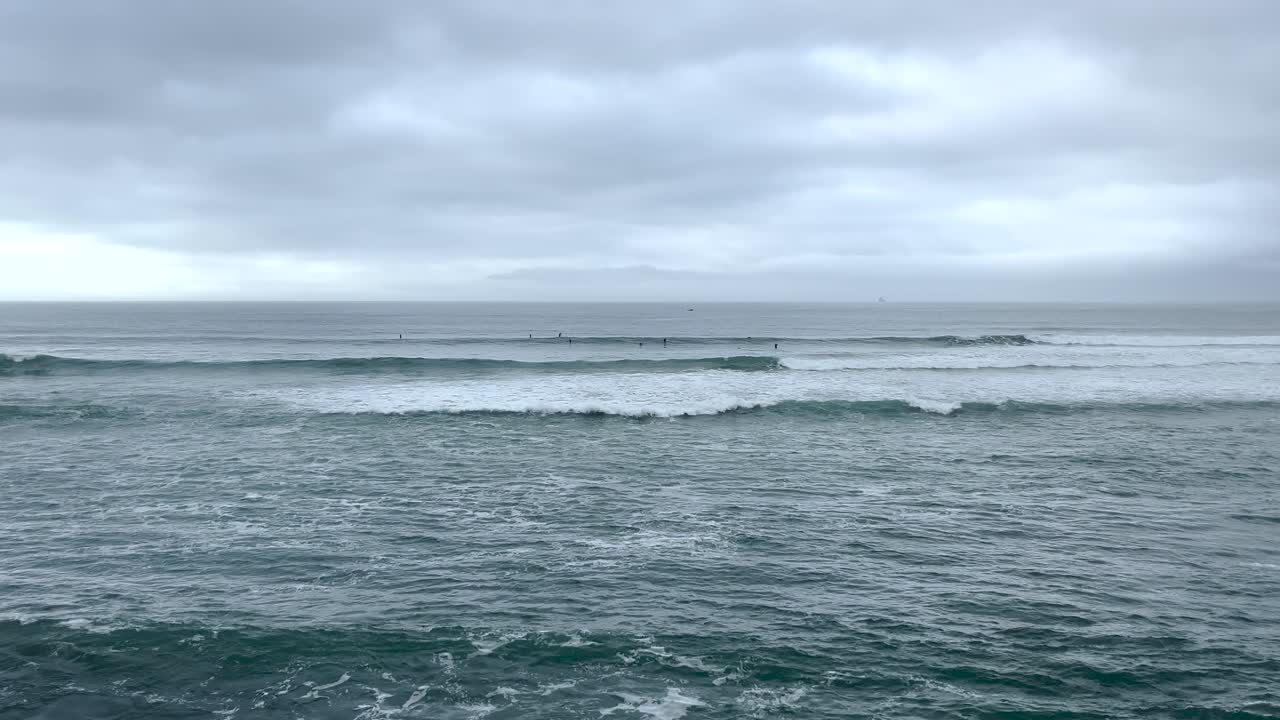 Surfers with the waves breaking in the ocean waters in Cascais, Portugal. Water sports.