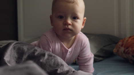a baby girl in pink romper suit on a messy bed