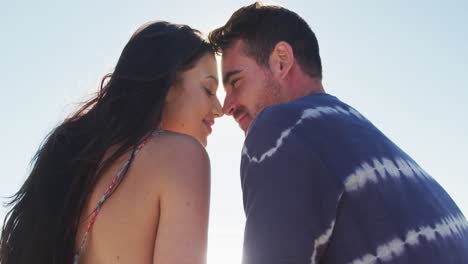 una feliz pareja caucásica sentada junto al mar coqueteando