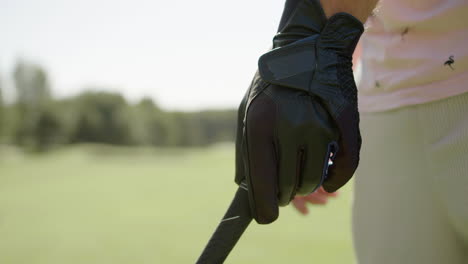Hand-in-glove-grabbing-golf-club,-ready-to-hit-the-ball-on-the-field