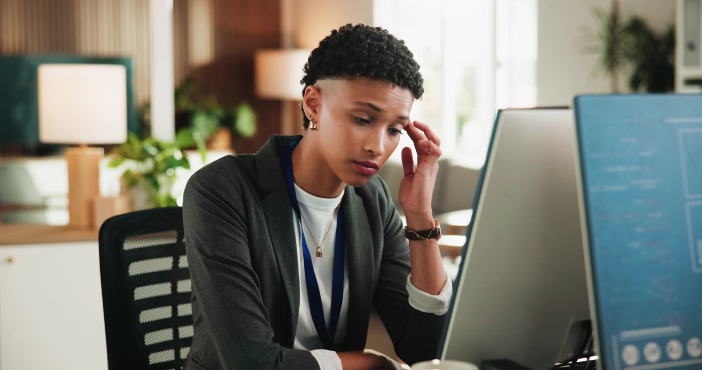 Stressed Businesswoman Rubbing Her Temples While Working at Office Desk