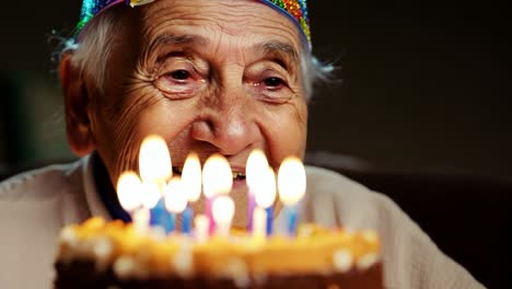 elderly woman blowing out candles on birthday cake