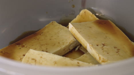 adding soy sauce to tofu slices for marinade - closeup shot