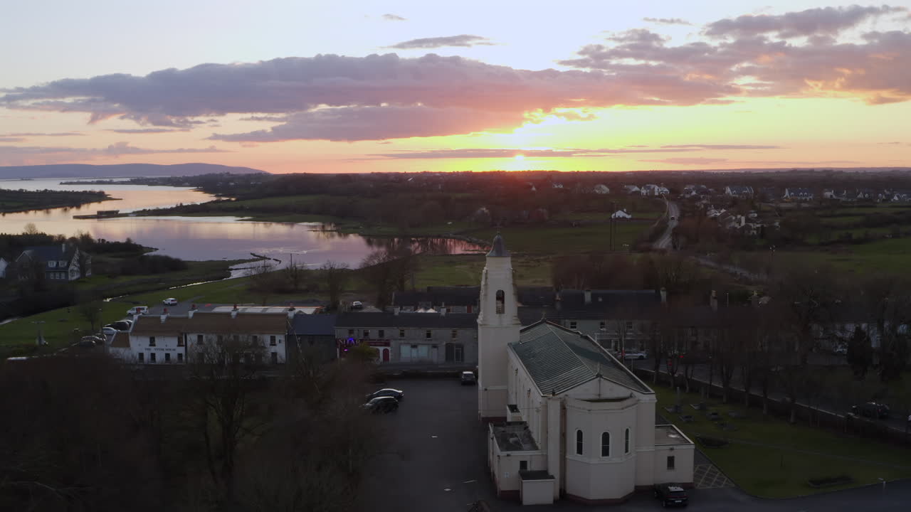 Aerial of Clarinbridge church rooftops and sunset sky casting warm tones over the townscape in Ireland